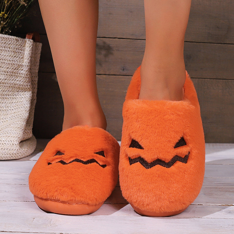 Orange pumpkin plush slippers with jack-o'-lantern faces, worn front view