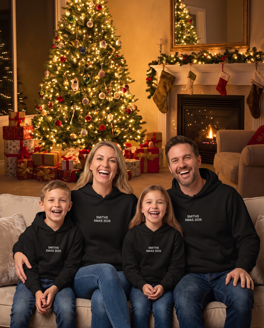 Family in matching custom Christmas hoodies by the tree
