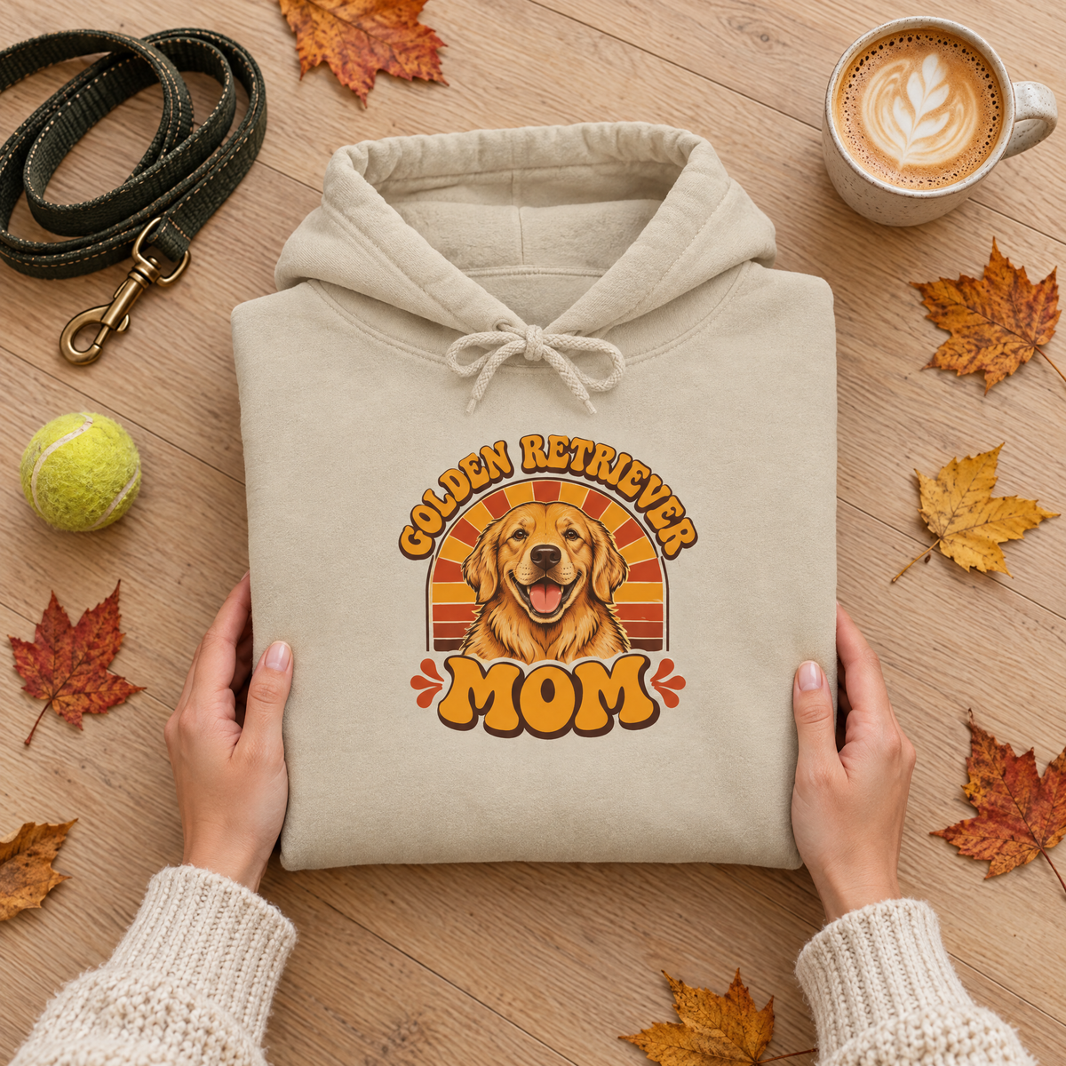 Golden Retriever Mom hoodie folded flat lay with a leash, tennis ball, latte and autumn leaves