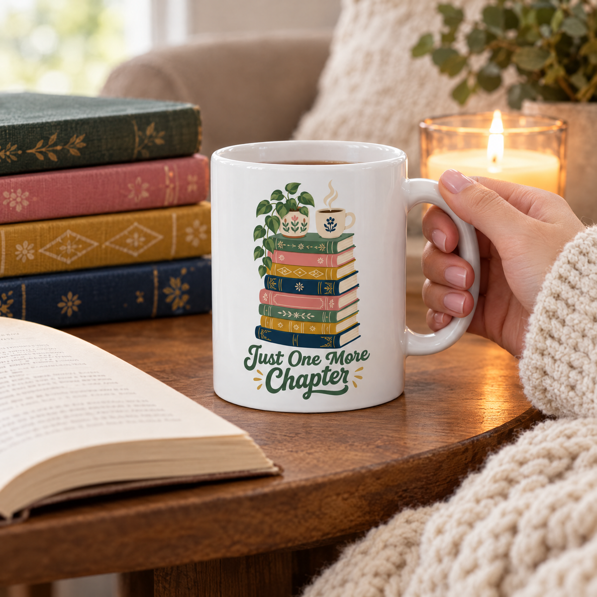 Just One More Chapter mug beside an open book, a stack of novels and a candle