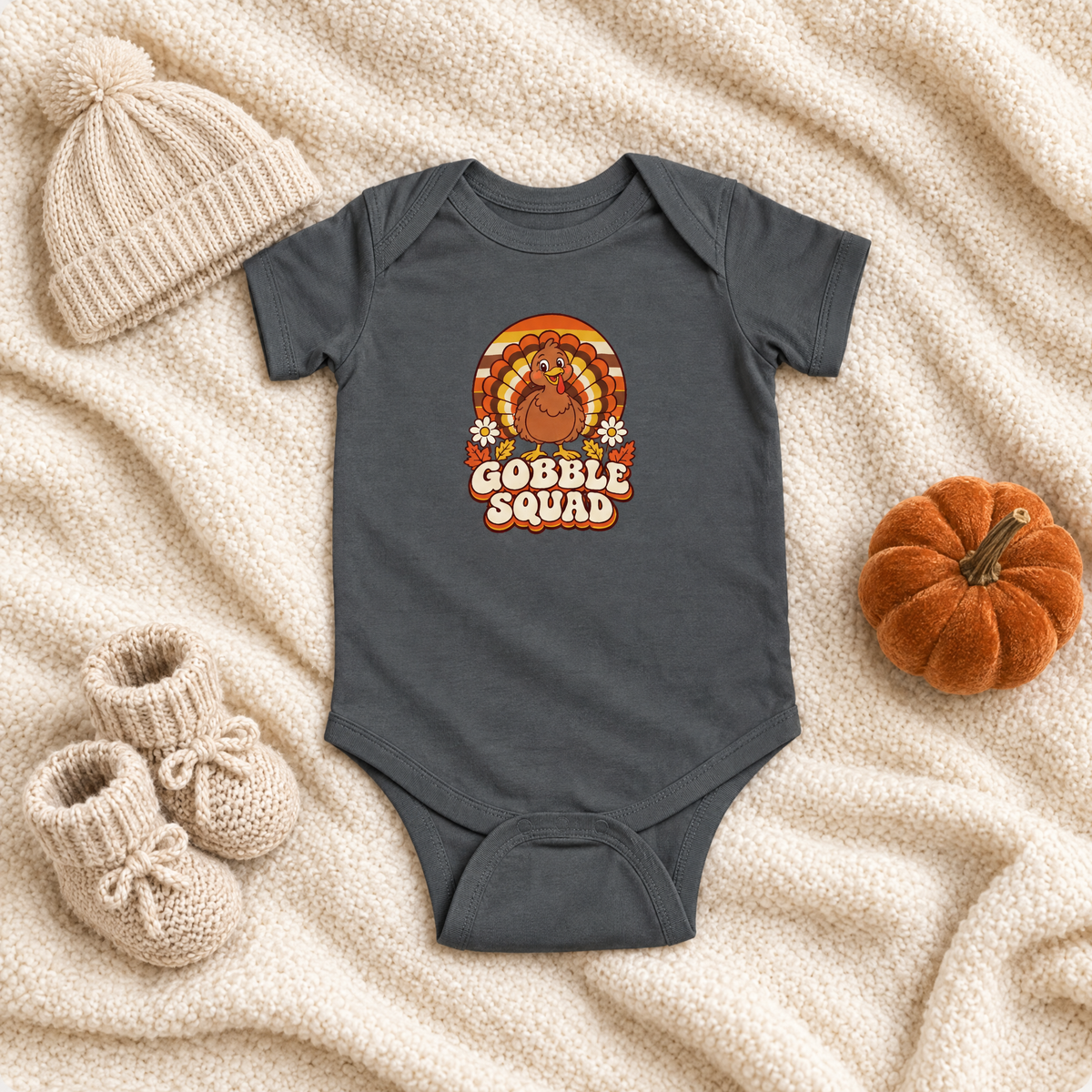 Gobble Squad turkey baby bodysuit flat lay with a knit hat, booties and a velvet pumpkin