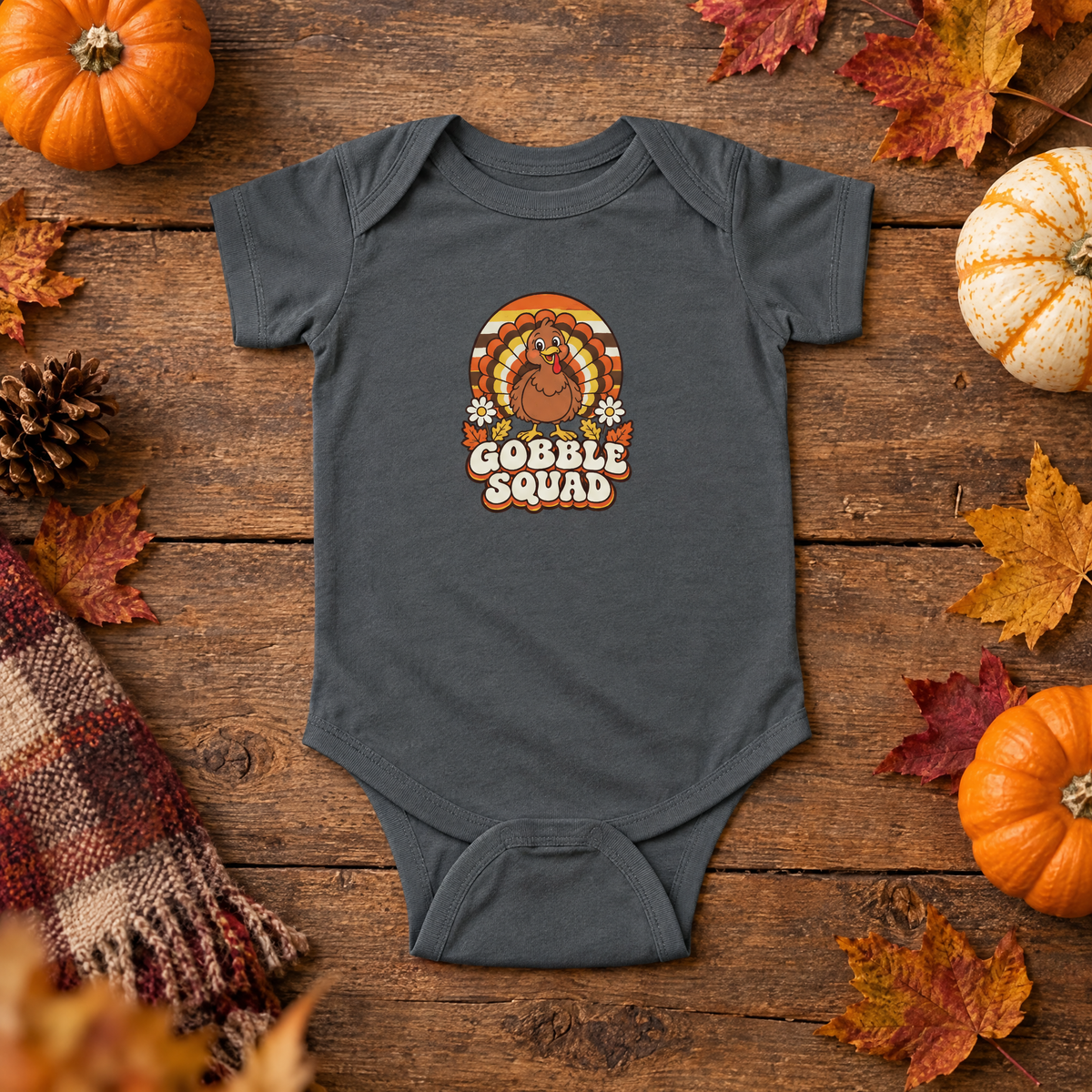 Charcoal Gobble Squad baby bodysuit flat lay on rustic wood with mini pumpkins and autumn leaves